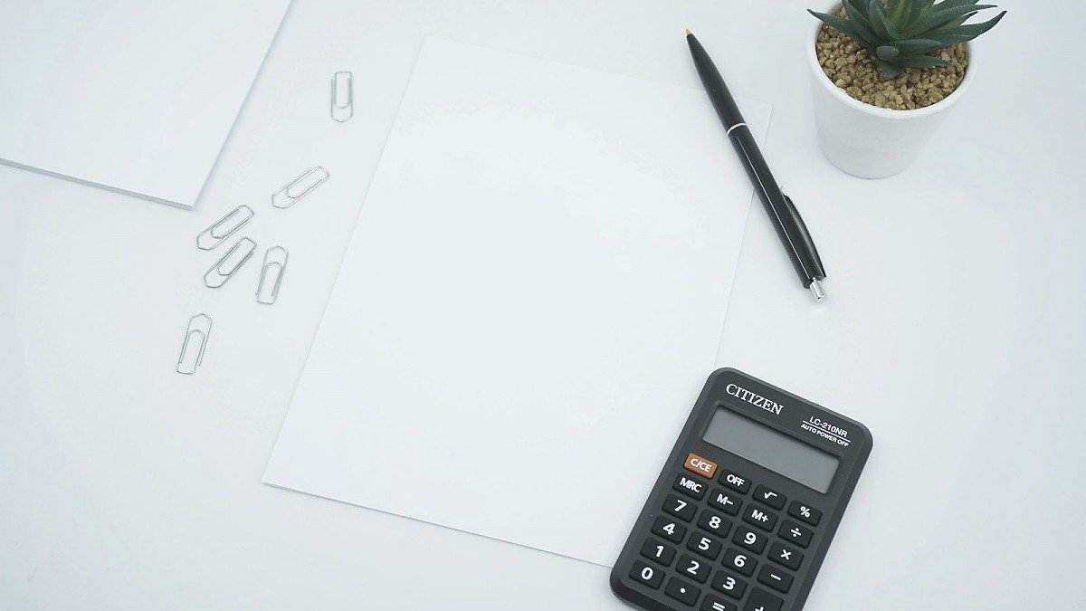 Schreibtisch mit Taschenrechner, Stift und Papier