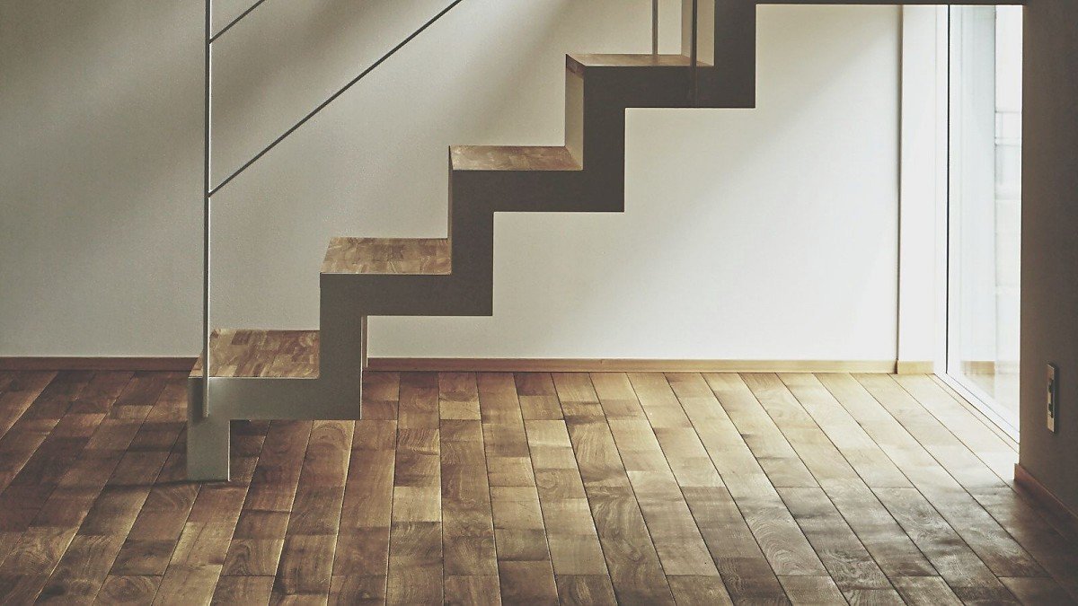 Leerer, heller Raum mit Holztreppe und Parkettboden